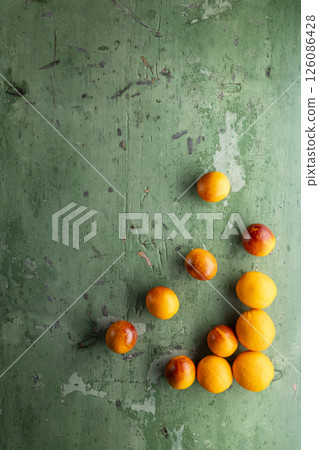 Fresh oranges lying on a green wooden table creating a design 126086428