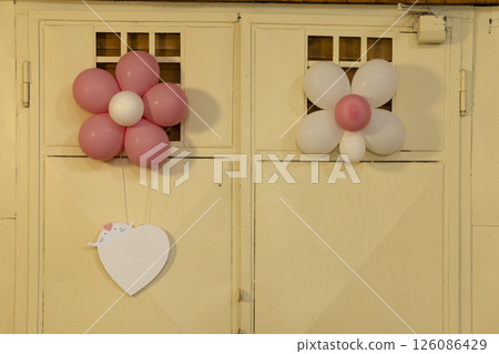 Pink and white flower shaped balloons hanging on a door with a heart shaped card Pink and white flower shaped balloons hanging on a door with a heart shaped card 126086429