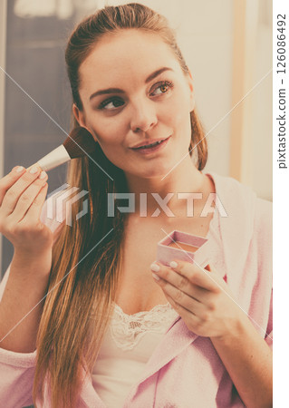 Woman applying bronzing powder with brush to her skin Woman applying bronzing powder with brush to her skin 126086492