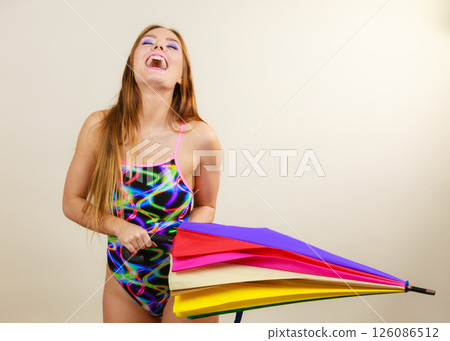 Happy woman posing in swimsuit and colorful umbrella Happy woman posing in swimsuit and colorful umbrella 126086512