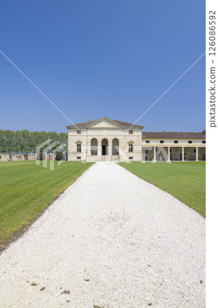 Historic villa with a gravel path and lush green lawns 126086592