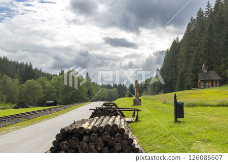 Scenic countryside with stacked logs and rustic cabin Scenic countryside with stacked logs and rustic cabin 126086607