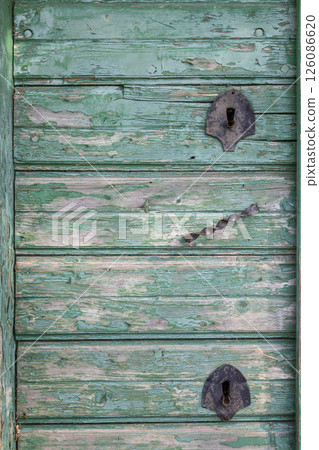 Weathered green wooden door with rusty metal hinges and handle in Wildendurnbach, Austria 126086620