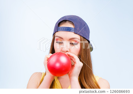 Female teenager inflating red balloon. Female teenager inflating red balloon. 126086693