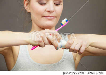 Woman holding toothbrush and placing toothpaste on it Woman holding toothbrush and placing toothpaste on it 126086701
