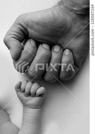Two hands: man and child. Father and son touching fists. Dad and newborn son boys holding hands together. Little and big fists of father and son. Black and white professional photo.  126087284
