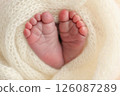 Soft feet of a newborn in a white woolen blanket. Close up of toes, heels and feet of a newborn baby 126087289