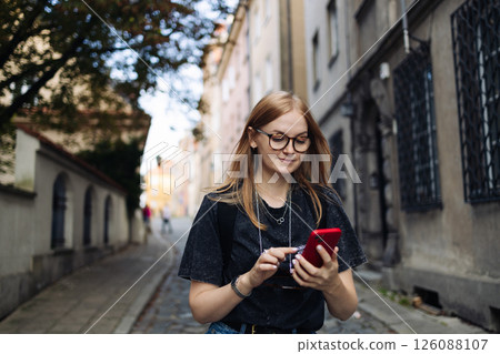 Young woman browsing smartphone while walking outside Young woman browsing smartphone while walking outside 126088107