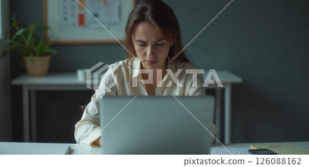 Stressed employees working at laptops showing fatigue and frustration during long work hours 126088162