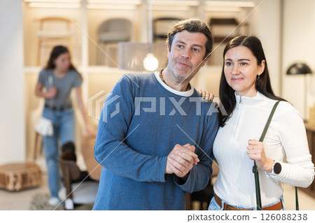 Man and woman talking friendly while looking for functional furniture and accessories in modern store 126088238