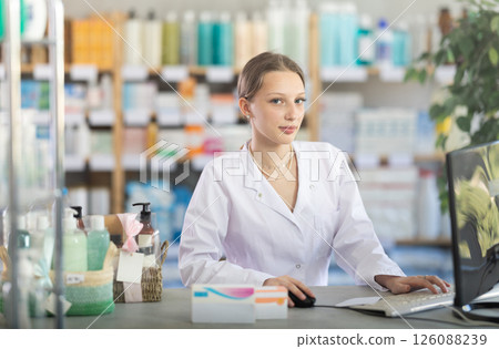 Young female pharmacist searches for information about medicines on Internet 126088239