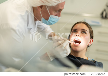Elderly male dentist examining female patient Elderly male dentist examining female patient 126088264