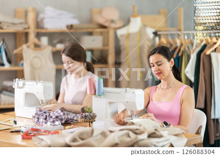 Two seamstresses working on sewing machines in sewing workshop Two seamstresses working on sewing machines in sewing workshop 126088304