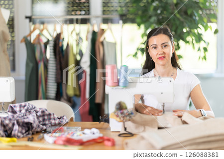 Woman seamstress sews on sewing machine in workshop 126088381