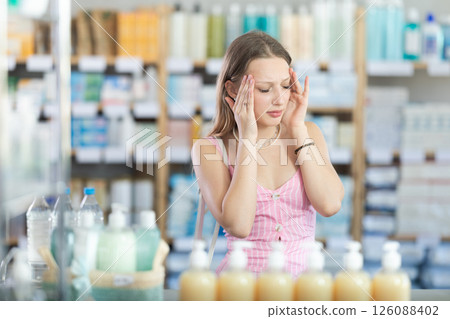 Woman with headache in pharmacy 126088402
