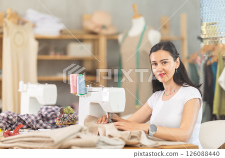 Woman seamstress sews on sewing machine in workshop 126088440