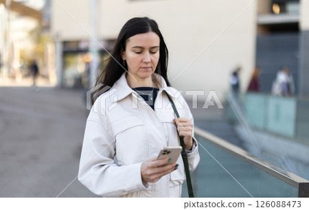 Girl traveler with phone walks through tourist area of town 126088473