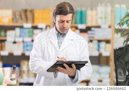 Man pharmacist makes restock, uses electronic carrier tablet of information Man pharmacist makes restock, uses electronic carrier tablet of information 126088482