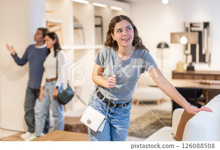 Woman looking at the upholstery of a sofa in a store 126088508