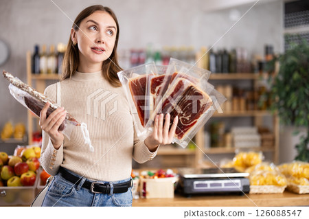 Girl looking at hamon and dried sausage in store Girl looking at hamon and dried sausage in store 126088547