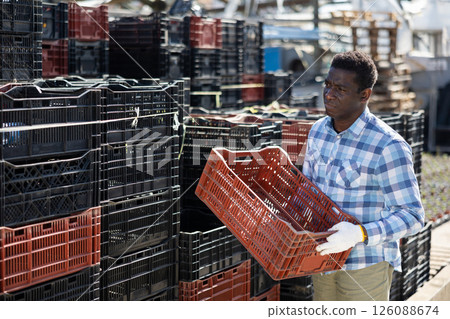 Worker stacking crates in outdoors warehouse 126088674