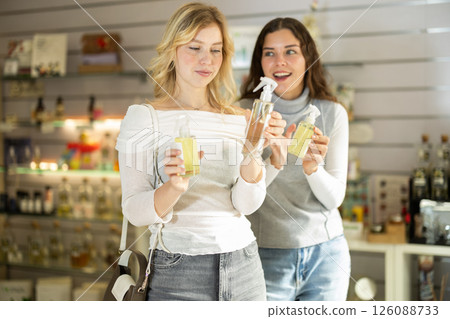 Two girlfriends choose aromatic perfumes together in perfume shop Two girlfriends choose aromatic perfumes together in perfume shop 126088733