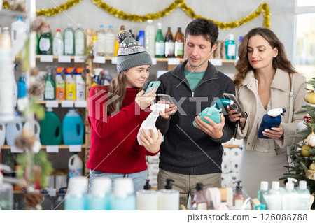 Family scanning barcodes on cleaning spray bottles with phones in festive store 126088788