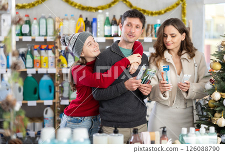 Father, mother and daughter choose toothbrush in supermarket 126088790