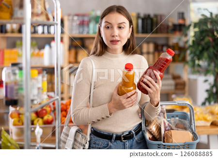 Young woman choose consider juice in store Young woman choose consider juice in store 126088885