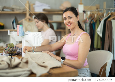 Two women tailor sews clothes in sewing machine Two women tailor sews clothes in sewing machine 126088886