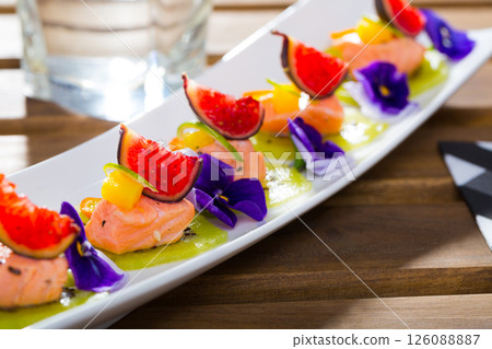 Ceviche from red trout on plate with cumquat, kiwi, figs and flower Ceviche from red trout on plate with cumquat, kiwi, figs and flower 126088887