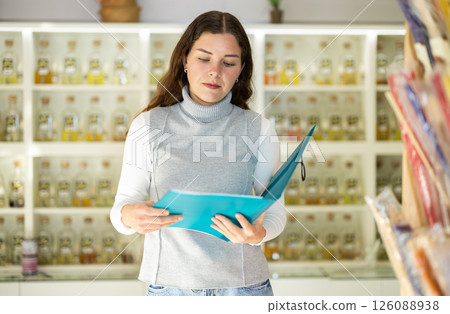 Girl seller with paper document make inventory in perfume store Girl seller with paper document make inventory in perfume store 126088938
