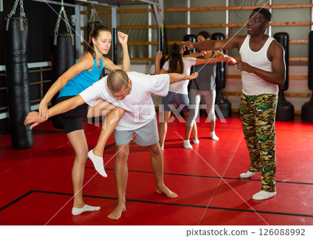 Woman learning knee strike during group self-defence training 126088992