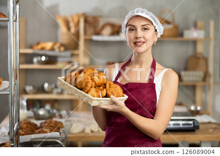 Young female baker with basket of croissants Young female baker with basket of croissants 126089004