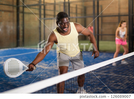Expressive energetic aframerican man playing padel indoors Expressive energetic aframerican man playing padel indoors 126089007