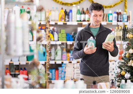 Adult man buyer chooses dishwashing in decorated store Adult man buyer chooses dishwashing in decorated store 126089008