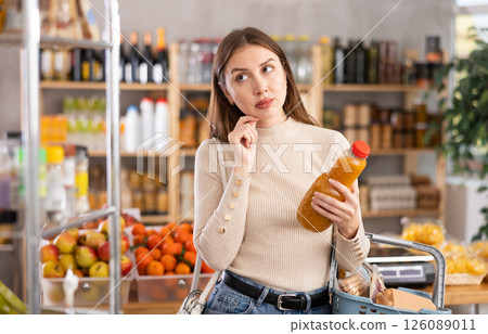 Young woman choosing peach juice in grocery store Young woman choosing peach juice in grocery store 126089011