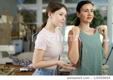 Woman customer examines finished product in presence of female tailor Woman customer examines finished product in presence of female tailor 126089064