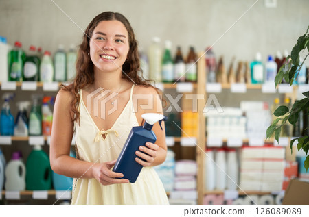 Young woman chooses cleaning spray in store Young woman chooses cleaning spray in store 126089089