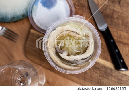 Marinated herring with onions and spice in plastic jar 126089165