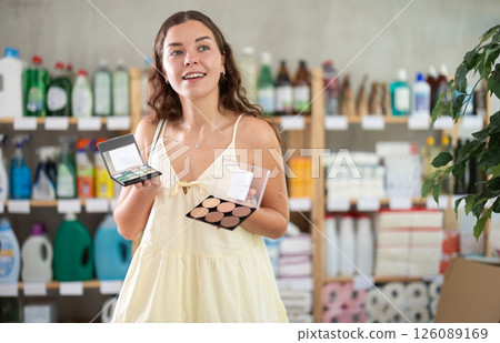 Girl choose highlighter and eye shadow pallet in household shop Girl choose highlighter and eye shadow pallet in household shop 126089169