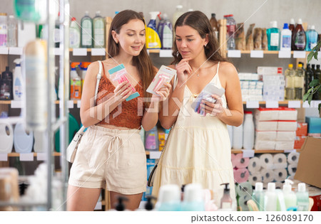 Two girls friends choose disposable razor in household shop Two girls friends choose disposable razor in household shop 126089170