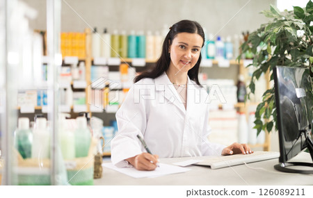 Middle-aged female pharmacist restocking with paper in drugstore Middle-aged female pharmacist restocking with paper in drugstore 126089211
