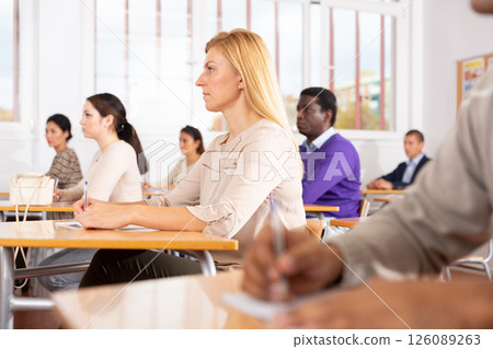 Interested adult woman sitting on lesson in school auditorium Interested adult woman sitting on lesson in school auditorium 126089263