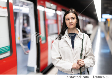 Girl is standing on metro platform station, waiting for transport to arrive 126089280