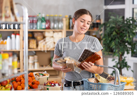 Grocery shopping at supermarket - girl chooses sweets, nougat, cookies and candies 126089305