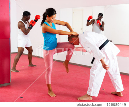 Woman is practicing self-defence fight in pair with trainer in gym 126089449