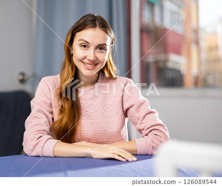 Portrait of a positive and confident young woman sitting at a table 126089544