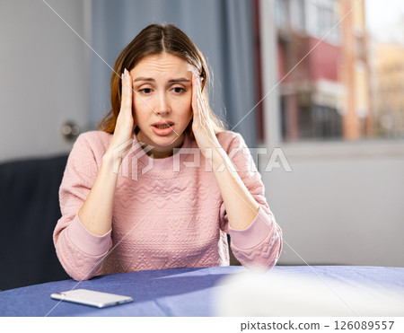 Portrait of a frustrated young woman sitting at a table Portrait of a frustrated young woman sitting at a table 126089557