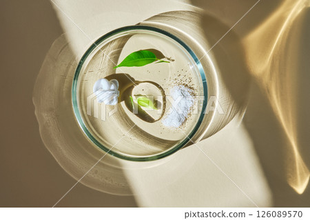 A swatch with textures of several skin care products in a petri dish on a beige background. 126089570
